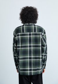 Grün-schwarz kariertes Hemd mit langen Ärmeln, einem Button-Down-Kragen und einem strukturierten Stoff, der weiße Gitterakzente aufweist.