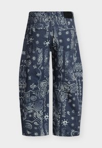 Široke hlače tamnoplave boje s uzorkom bijelog cvijeća i paisley uzorka na bandana tkanini, s stražnjim džepovima i crnom naljepnicom na pojasu.