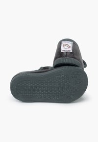 Zapatillas infantiles de terciopelo negro con suela de goma. Cuentan con un parche colorido de mono y una correa ajustable para poner y quitar fácilmente.