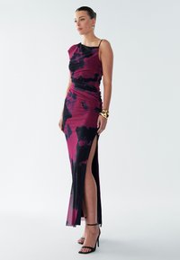 Priliehavé šaty na jedno rameno v burgundskej farbe s čiernymi abstraktnými vzormi, so zvýšeným rozparkom a nariasenou textúrou na živôtiku.