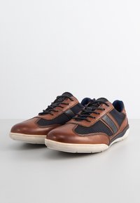 Brown leather and navy mesh sneakers with black laces, a textured upper, and a cream rubber sole, featuring a side logo detail.