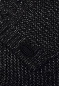 Wełniana czapka w ciemnych odcieniach czerni i szarości, z teksturowanym wzorem oraz płaską naszywką z czarnego materiału z wytłoczonym napisem.