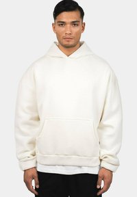 White hoodie made of soft fabric, featuring a front pocket, a drawstring hood, and a loose fit. Sleeve cuffs and bottom are ribbed.