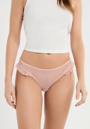 Mutandine rosa a pois realizzate in tessuto trasparente con bordo arricciato. Presentano una cintura smerlata e una texture delicata. Design semplice e femminile.