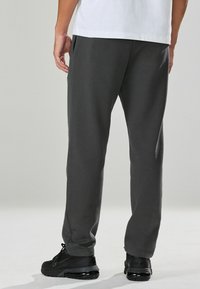 Grijze sweatpants van zachte stof met een rechte snit, voorzien van zijzakken en gecombineerd met zwarte sportschoenen.