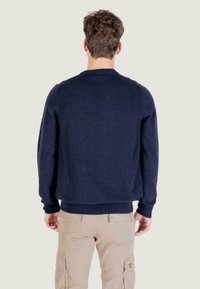 Maglione girocollo blu navy realizzato in morbido tessuto, con polsini e orlo a costine, finitura liscia e texturizzata. Vestibilità casual.