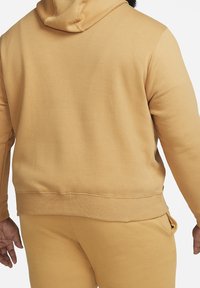 Žlutá mikina s kapucí a volným střihem, s žebrovanými manžetami, s klokaní kapsou a hladkým, jemným materiálem, v kombinaci s odpovídajícími kalhotami.