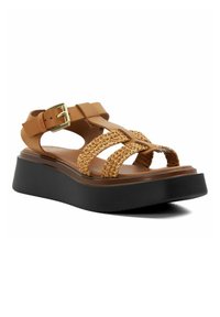 Sandale en wedge marron avec des accents en paille tissée, boucle ajustable et semelle noire. Design ouvert au niveau des orteils et plusieurs brides pour le soutien.
