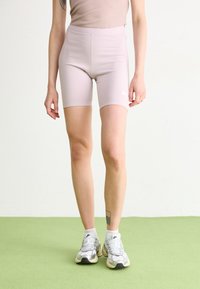 Shorts de ciclism roz deschis, cu talie înaltă, confecționați dintr-un material elastic, având un mic logo alb Nike pe piciorul stâng.