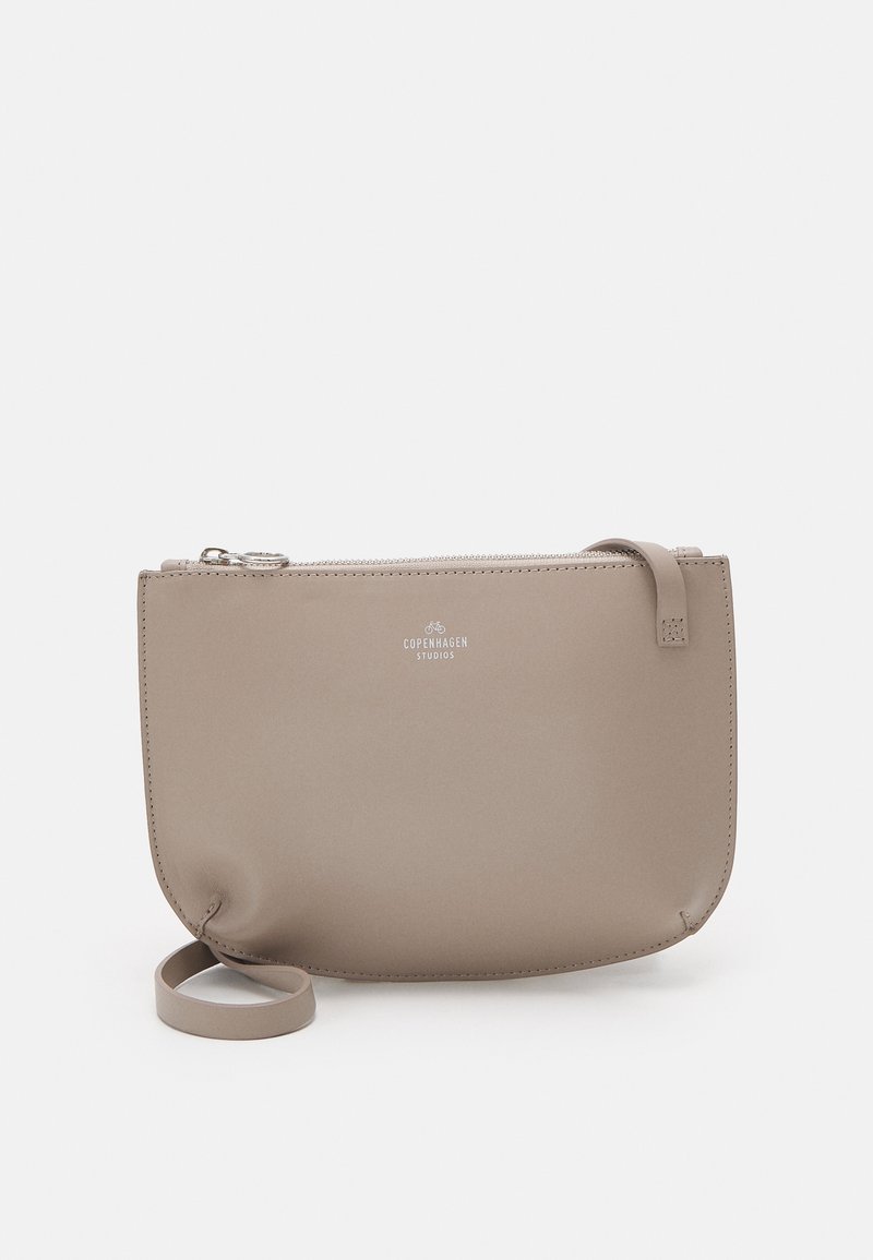 Bolso tipo pouch de cuero beige con textura lisa, cierre de cremallera y una correa en un lado. Presenta el logo "Copenhagen Studios" en el frente.