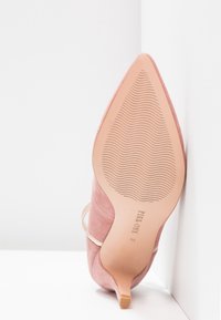 Chaussure à talon haut en daim rose à bout pointu avec semelle texturée et petit talon kitten, vue de dessous sur fond blanc.