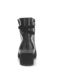 Bottine noire avec un matériau à motif serpent et une finition mate. Comprend un accent de sangle noire et un talon épais.