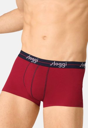 Rote Baumwoll-Boxershorts mit einem marineblauen elastischen Bund, der den Markennamen "Sloggi" in Weiß zeigt. Entworfen für Komfort und Passform, mit glatter Textur.