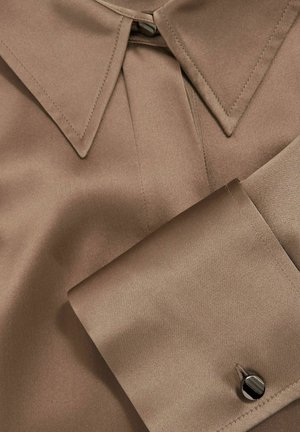 Braune Satinbluse mit einem klassischen Kragen, einem gefältelten Design am Hals und einem kontrastierenden Knopf an der Manschette. Glatte Textur.