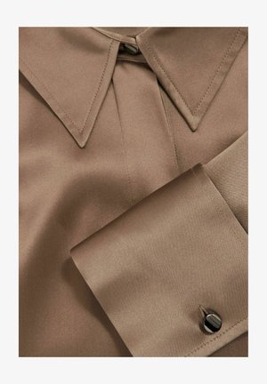 Chemise en satin marron avec un col classique, un design plissé au niveau du cou et un bouton contrastant sur le poignet. Texture lisse.