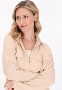 Beige bordázott ingdzseki gombos záródással, két elülső zsebbel és széles ujjakkal, puha tapintású anyagból. Könnyed és lezser dizájn.