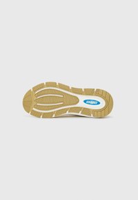 Såle av en sneakers med en teksturert gummioverflate. Lys brun farge med rillede mønstre og en hvit mellomsåle. Blå logo detalj.