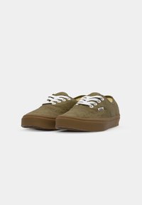 Olijfgroene canvas schoenen met witte veters, rubberen zolen en een eenvoudig ontwerp. Gestikte bovenkant en stevige constructie.