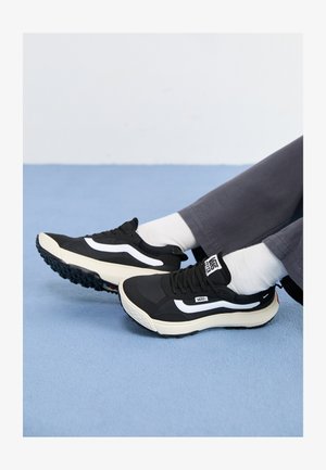 Mustad mustad tossud valgete aktsentidega, võrgumaterjalist ja kummist, millel on tekstureeritud tallad ja kand. Kandmise ajal valged sokid ja hallid püksid.