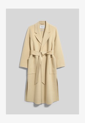 Long manteau en laine beige avec larges revers, deux poches plaquées devant et une ceinture en tissu assorti nouée à la taille, présenté à plat sur fond gris.