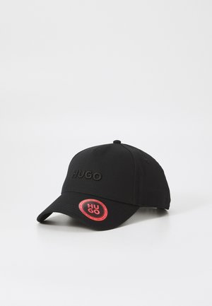 Melnā beisbola cepure ar izsistītu "HUGO" logotipu, izliekta mala un apaļa sarkana birka ar "HUGO". Izgatavota no izturīga auduma.