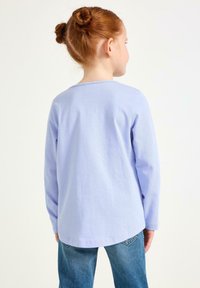 Langærmet, lyse lilla skjorte lavet af bomuld, med rundet halsudskæring og løs pasform, kombineret med blå jeans.