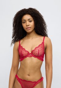 Σετ κόκκινου εσωρούχου με διάφανο σουτιέν κεντημένο με κυματιστά χείλη, δίχτυ με σχέδιο και αντίστοιχο μποξεράκι με διακοσμητικές βολάν.