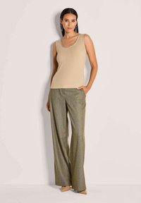Beige gerippter Tanktop mit Rundhalsausschnitt, kombiniert mit weitem, metallic-beige-grünem Hosen, die seitliche Taschen und einen subtilen Glanz aufweisen.