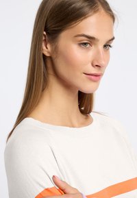 Lichtgrijze trui met oranje strepen, ronde halslijn en zachte brei-textuur. Casual pasvorm, zichtbare stiksels op de manchetten en de onderrand.