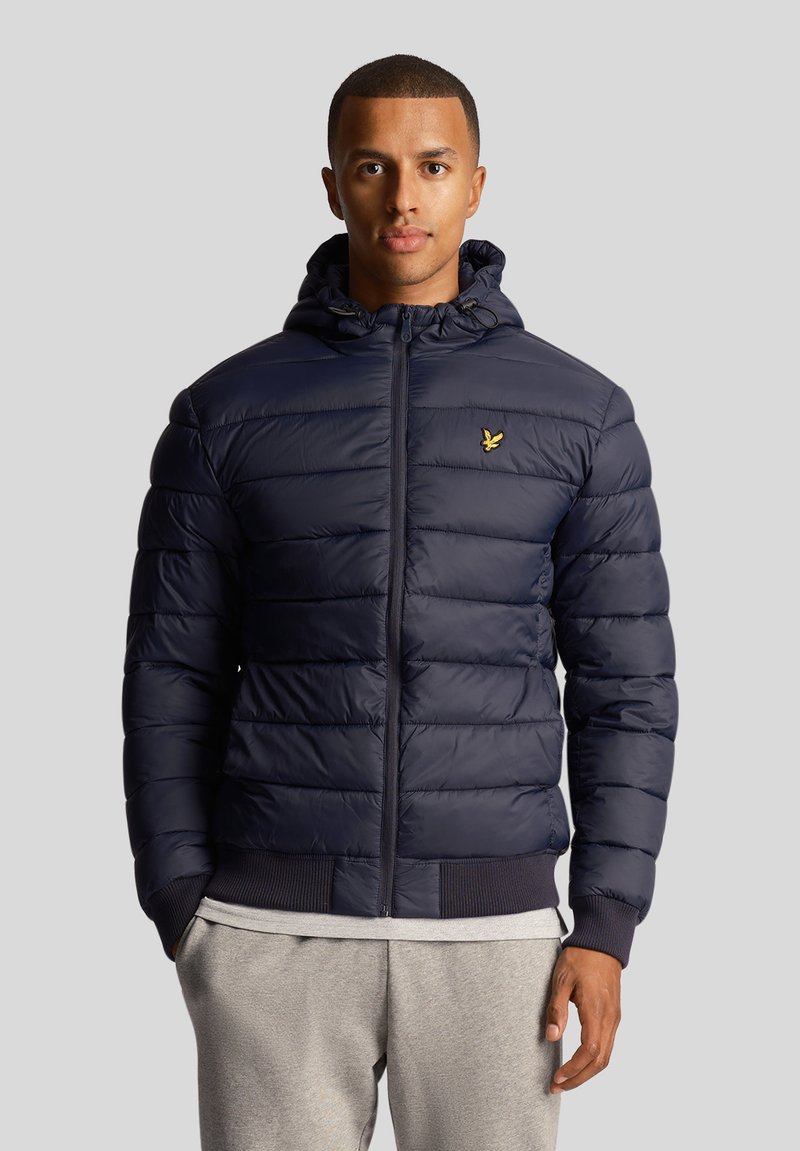 Navy puffer jacket with a zippered front, hood, ribbed cuffs, and hem. Features horizontal quilting and a small logo on the chest.