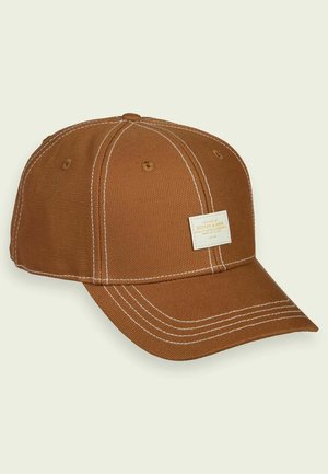 Casquette de baseball marron texturée avec des surpiqûres blanches contrastées et une petite étiquette rectangulaire en tissu sur le panneau avant.