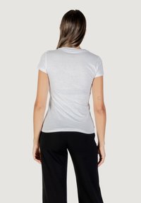 Witte t-shirt met korte mouwen en een getailleerde silhoutte, zachte stoftextuur en een ronde halslijn, weergegeven van achteren.