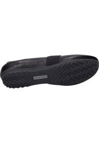 Black slip-on shoe with a textured rubber sole featuring a zigzag pattern, elastic strap for secure fit, and smooth upper finish.