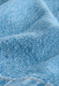 Tela de denim azul claro con un tejido de sarga visible, con una textura suave y sutiles variaciones de color.