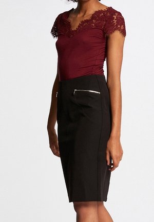 Bordeauxkleurige body met kanten rand, gecombineerd met een zwarte kokerrok met twee zakken met rits. Gladde textuur, getailleerde pasvorm.