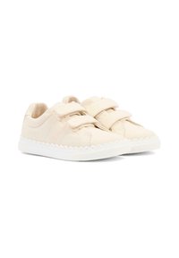Zapatillas de lona beige con dos cierres de Velcro, suelas de goma blancas, detalle de borde festoneado y marca sutil en el lateral.