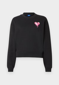 Sweat-shirt noir col rond manches longues avec un petit cœur rose dégoulinant sur la partie supérieure gauche de la poitrine.