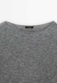 Pull en laine gris doux avec col rond, doté d'une texture fine en maille et d'une petite étiquette de marque noire à l'intérieur du col.