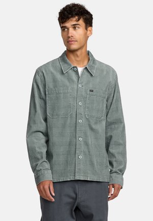 Green patterned shirt with a collared neck, button closure, two chest pockets, and a textured fabric. Long sleeves with elastic cuffs.