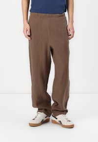 Brune linbukser med elastisk liv, med en avslappet passform og rette ben, kombinert med hvite sneakers.