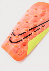 Orange fodboldskinne med hexagonal tekstur, sort logo og gul accent. Fastgøres sikkert og har forhøjede gummisektioner for beskyttelse.