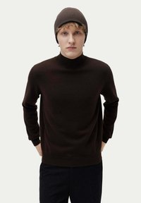 Brun, ribbad stickad turtleneck-tröja med långa ärmar och en avslappnad passform, parat med en matchande brun mössa.