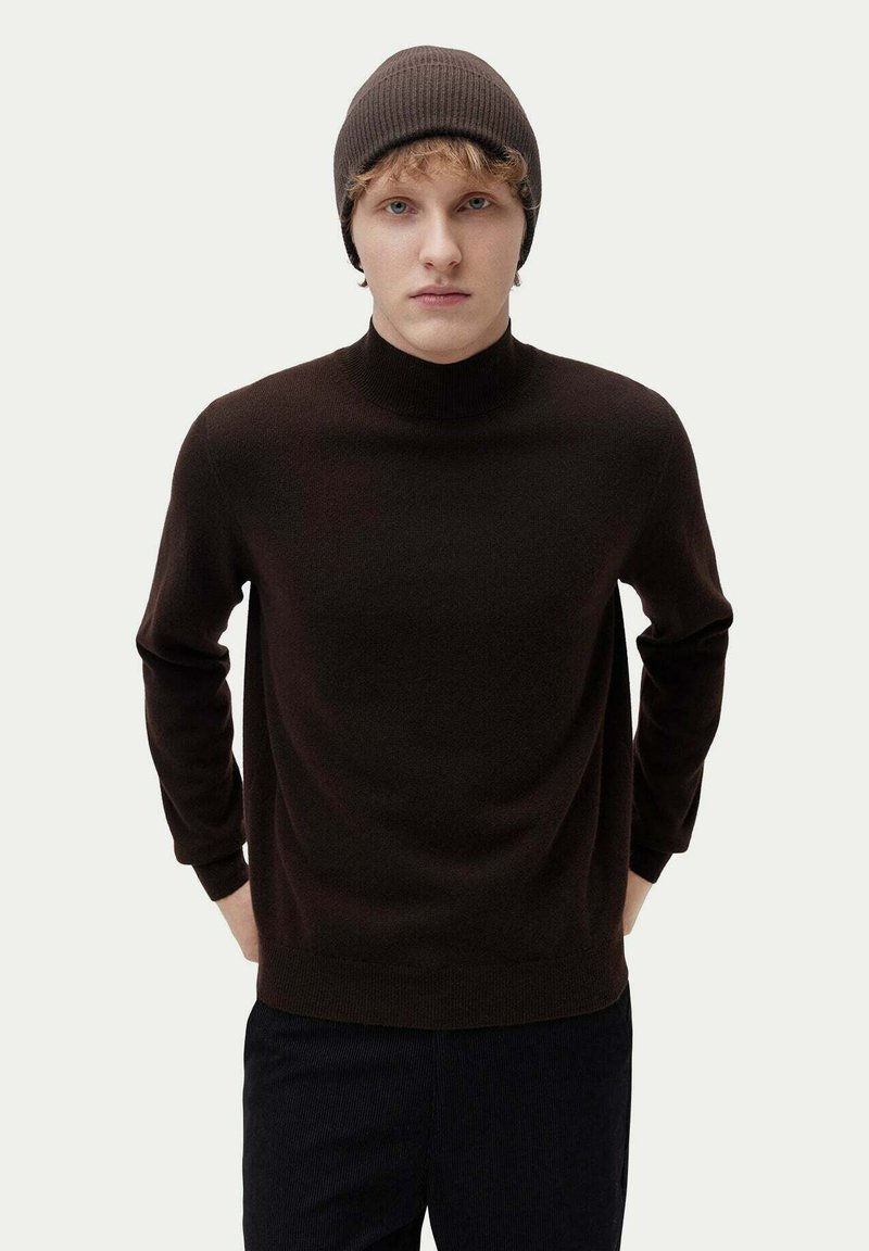 Brun, ribbad stickad turtleneck-tröja med långa ärmar och en avslappnad passform, parat med en matchande brun mössa.