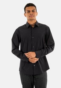Camisa negra de botones con cuello clásico y mangas largas. Presenta una textura suave y un ajuste entallado con sutiles detalles de botones.