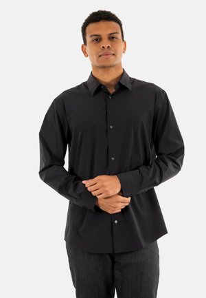 Camisa negra de botones con cuello clásico y mangas largas. Presenta una textura suave y un ajuste entallado con sutiles detalles de botones.