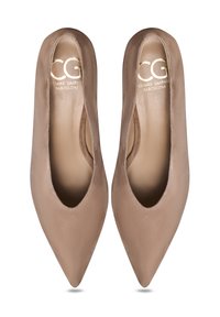 Talons aiguës en suède beige avec des côtés découpés. Texture lisse et design minimaliste, avec un branding doré subtil à l'intérieur.