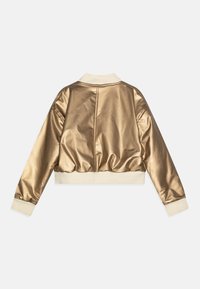 Zlata satenska bomber jakna s skrajšano zasnovo, kremnimi rebrastimi manšetami in robom, ki se ponaša z gladko teksturo in minimalnimi detajli.