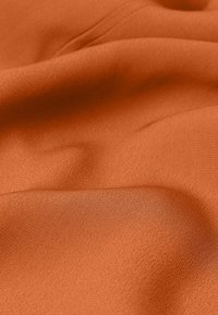 Hladká, oranžová tkanina s jemnou, mírně lesklou texturou, která vykazuje jemné vlnité vzory a záhyby. Lehký, univerzální materiál.