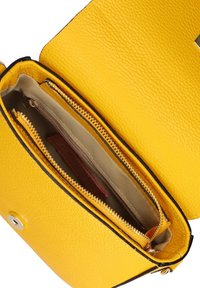 Borsa a tracolla gialla in pelle aperta per mostrare l'interno con foderatura beige e una tasca con zip all'interno.