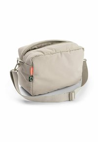 Beige téglalap alakú puha válltáska állítható pánttal, elülső cipzáros zsebbel és kis narancssárga és zöld öko-barát címkékkel az oldalán.